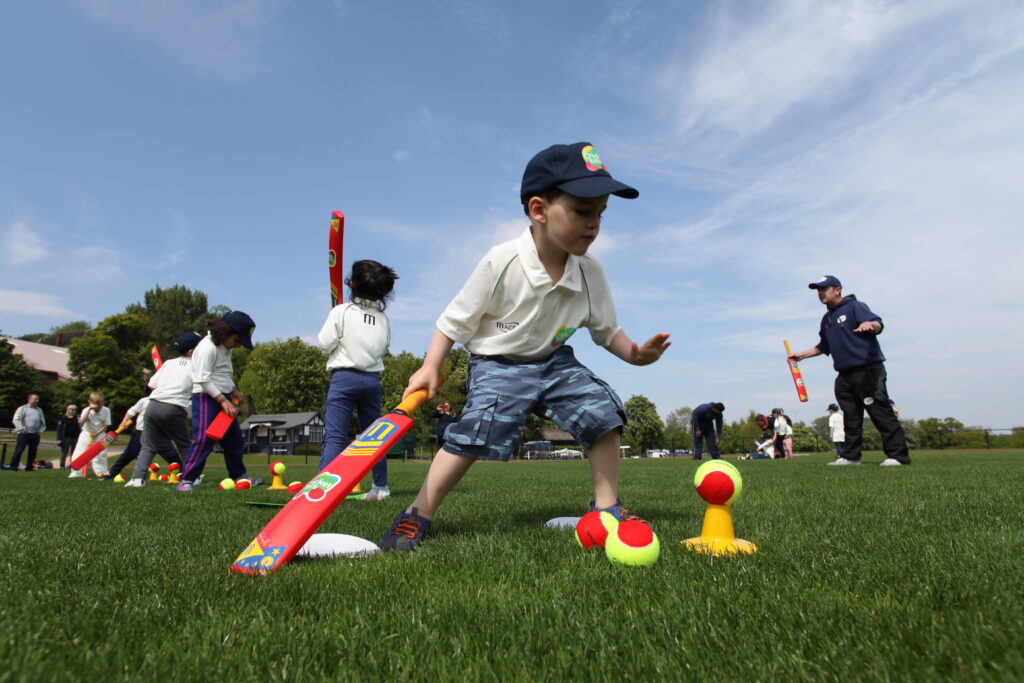 boy holding cricket bat and balancing cricket balls